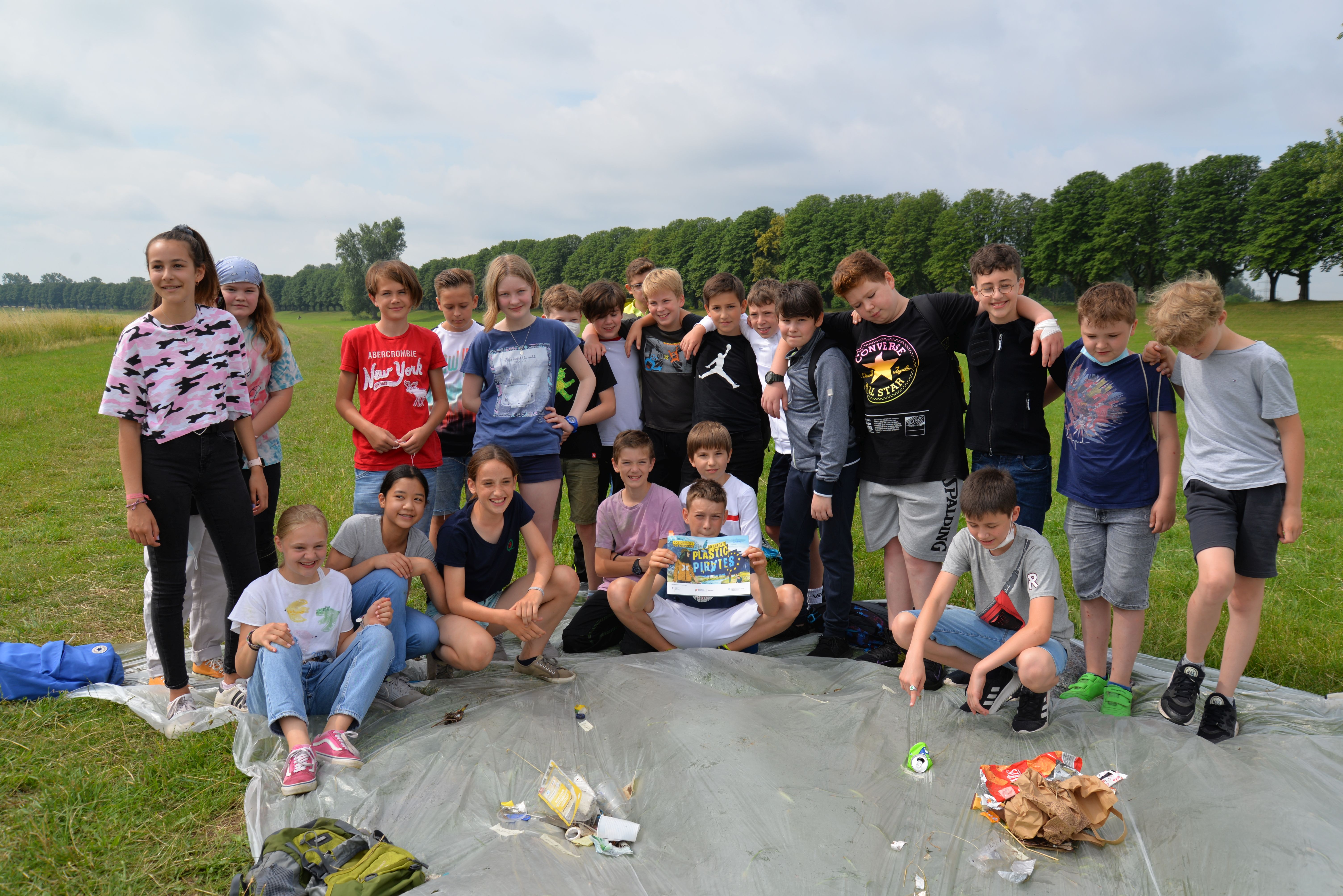 Schüler*innen der 6c stehen auf der Rheinwiese in Neuss und untersuchen den vor ihnen liegenden Plastikmüll